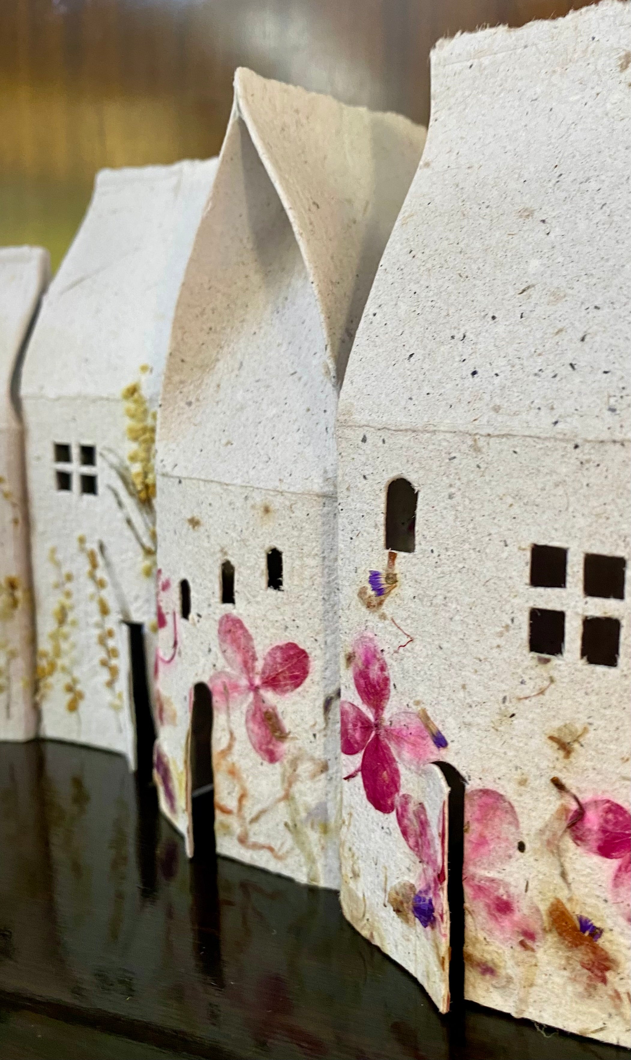 Decorative paper houses with floral patterns on a dark surface
