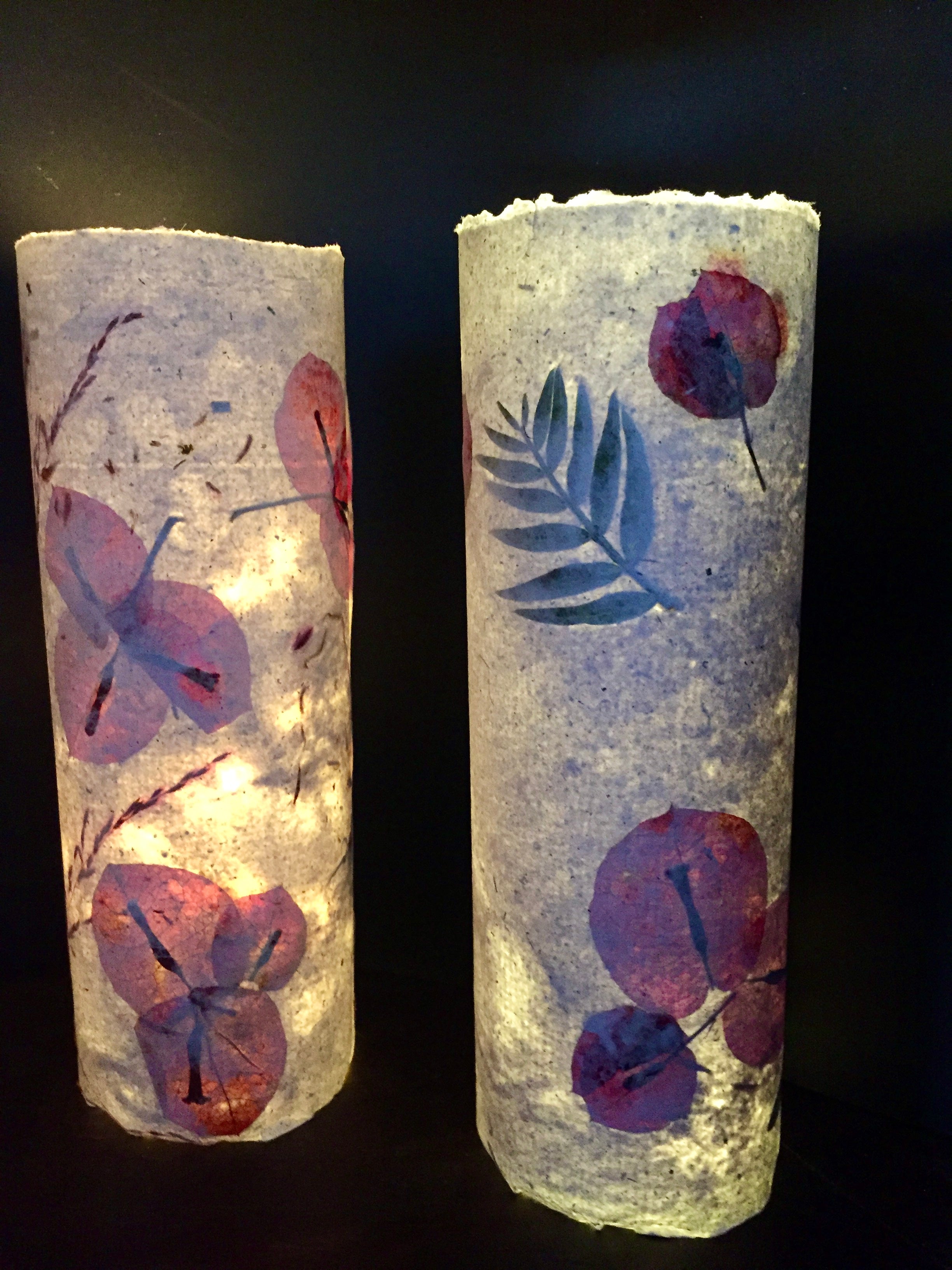 Two cylindrical paper lanterns with leaf patterns on a dark background