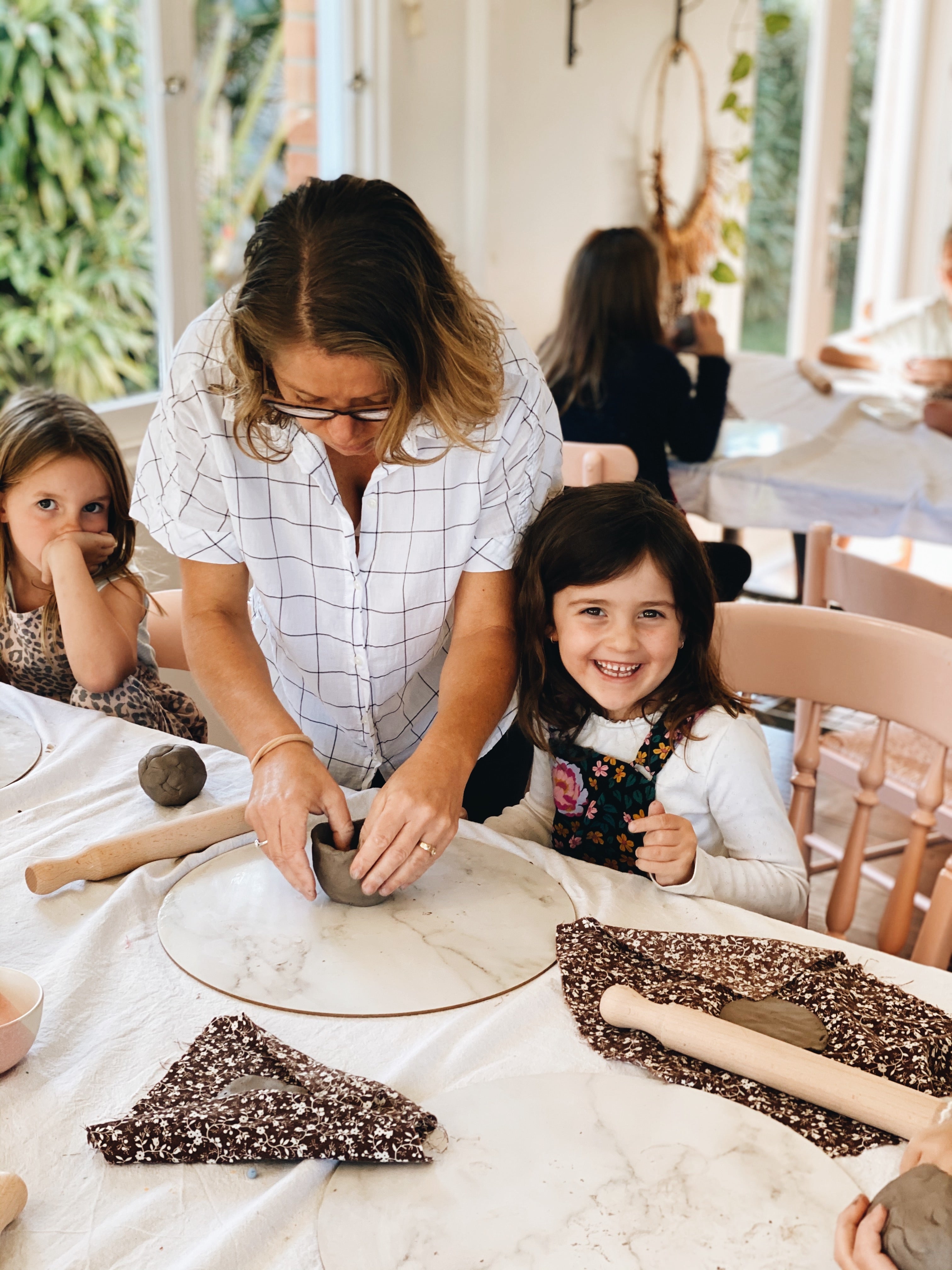Girl getting help by teacher during kids pottery class