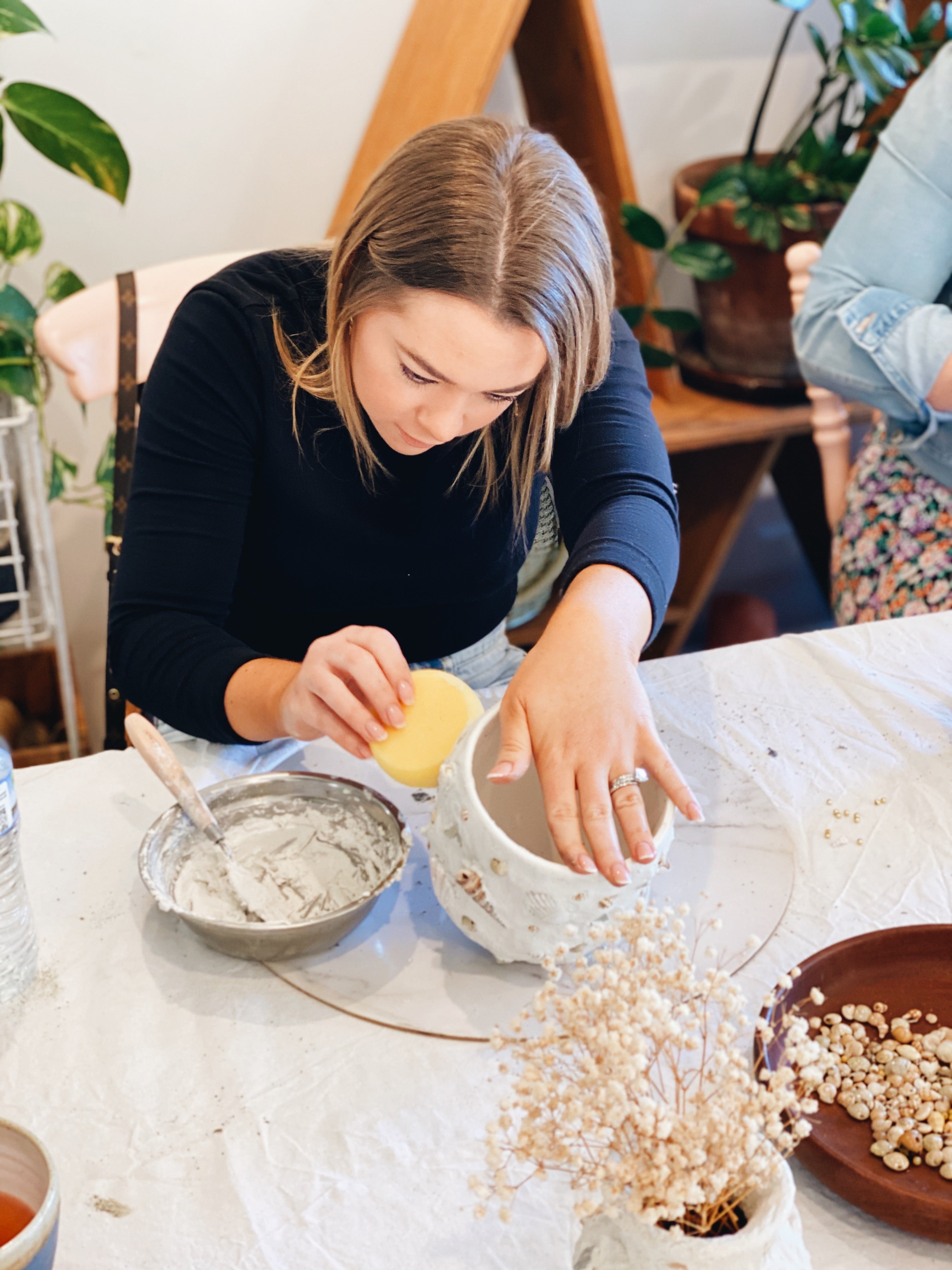 Lady paying close attention while making her shell mosaic pot
