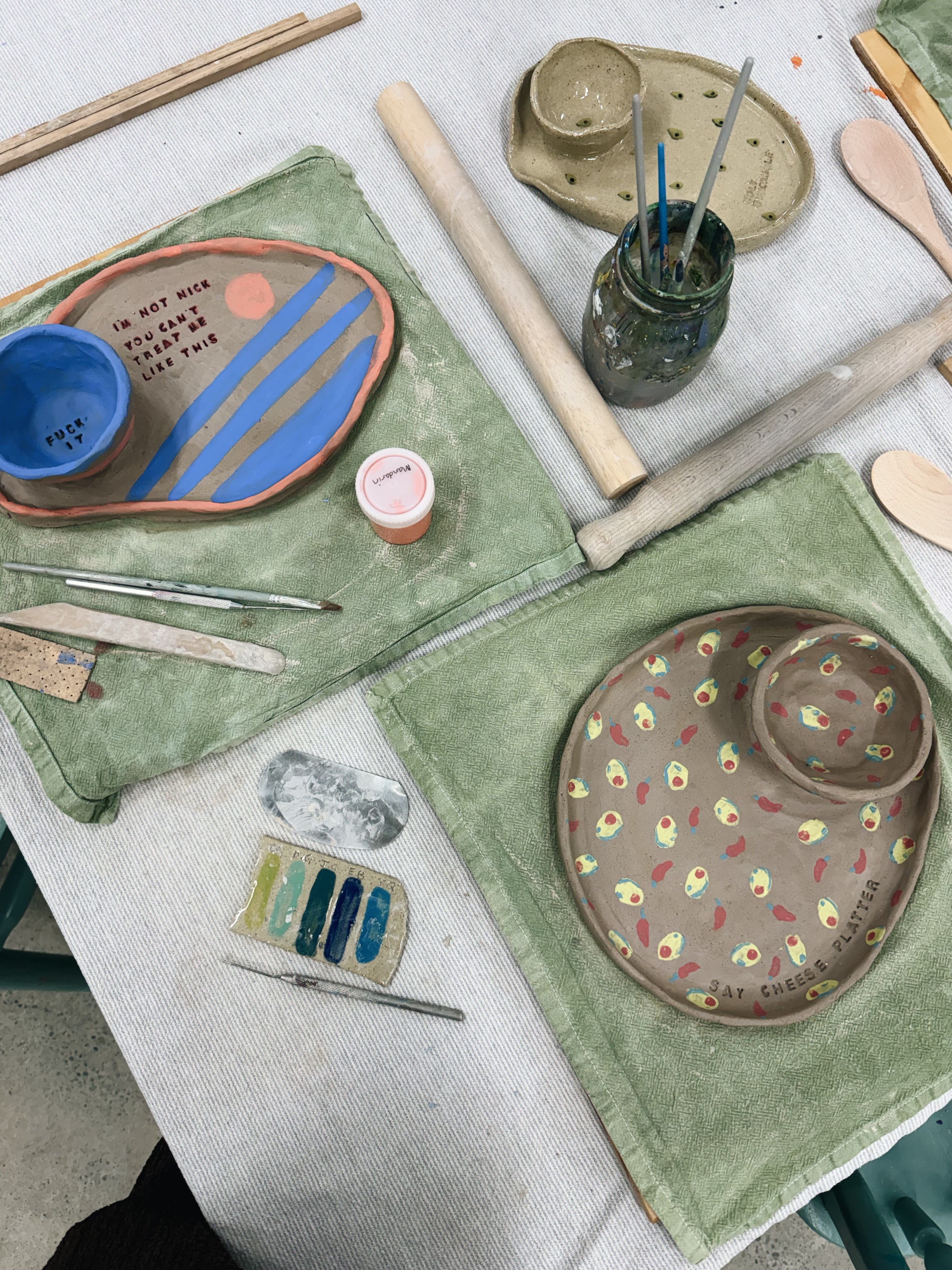 Tabletop scene with ceramic plates, tools, and materials on a white surface