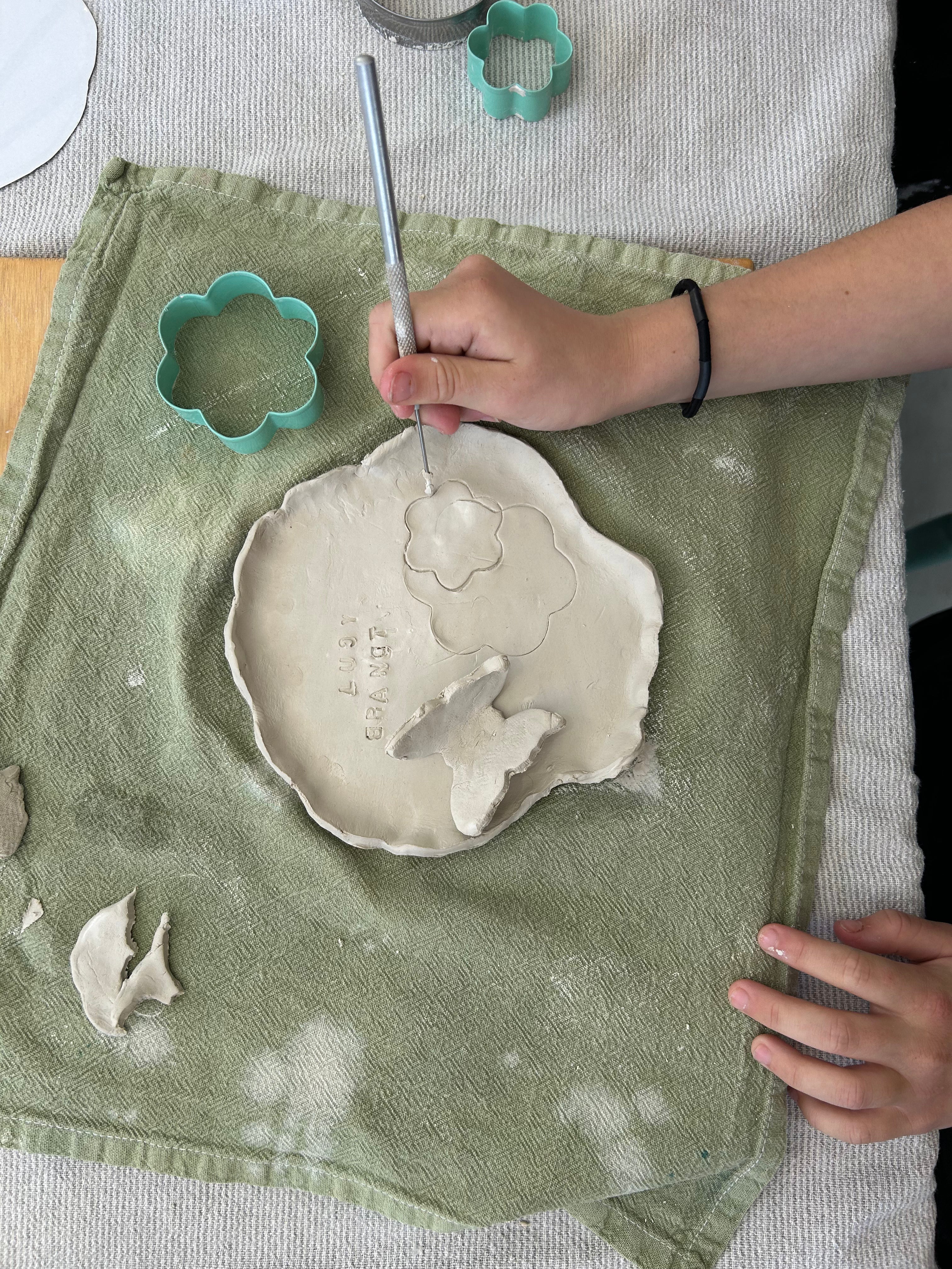 Person working with clay on a towel, using tools to shape the material.