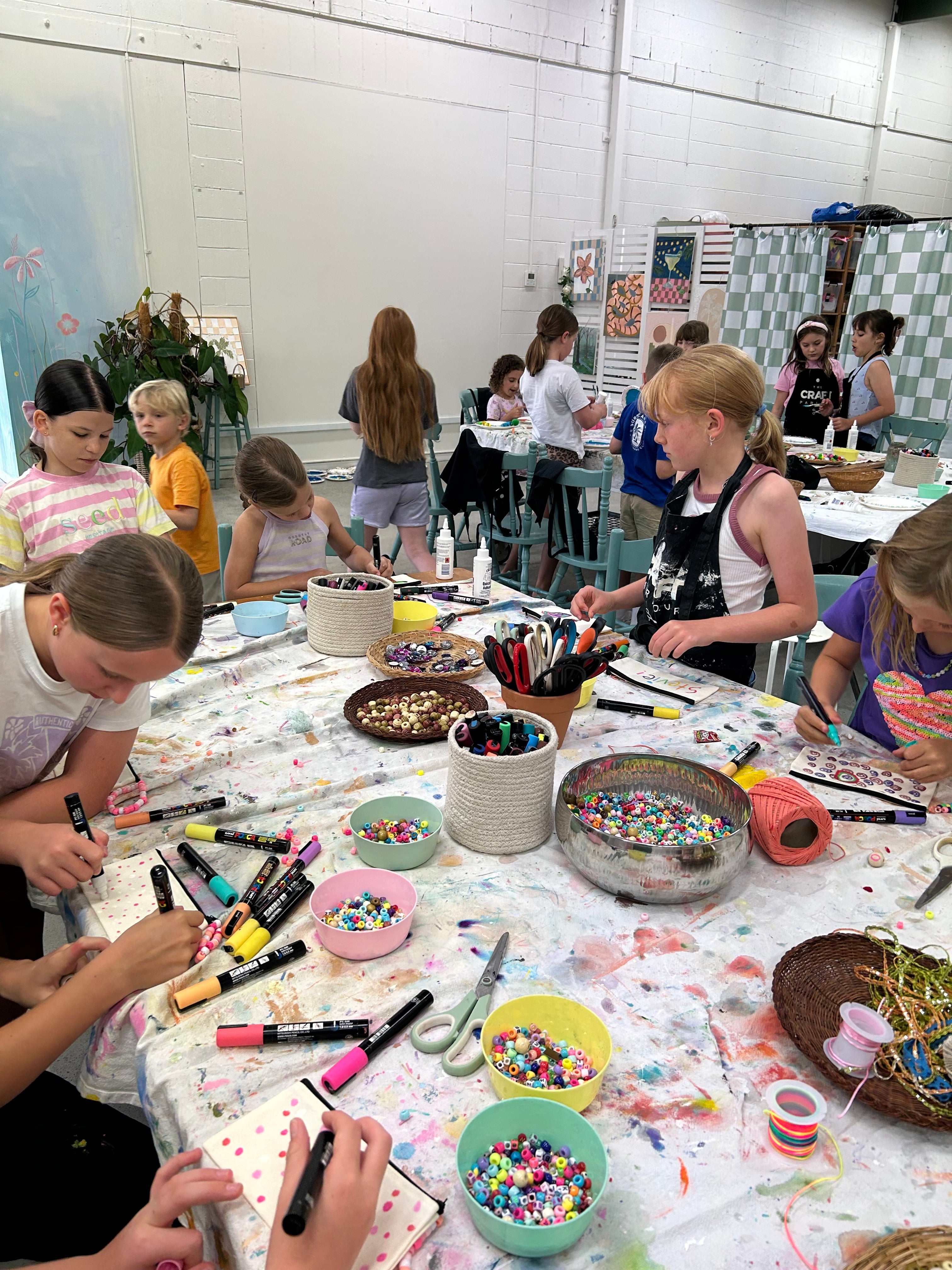 Children at a craft table with various materials and supplies