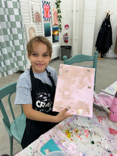 Child holding a pink marble-patterned box in a room with colorful decor