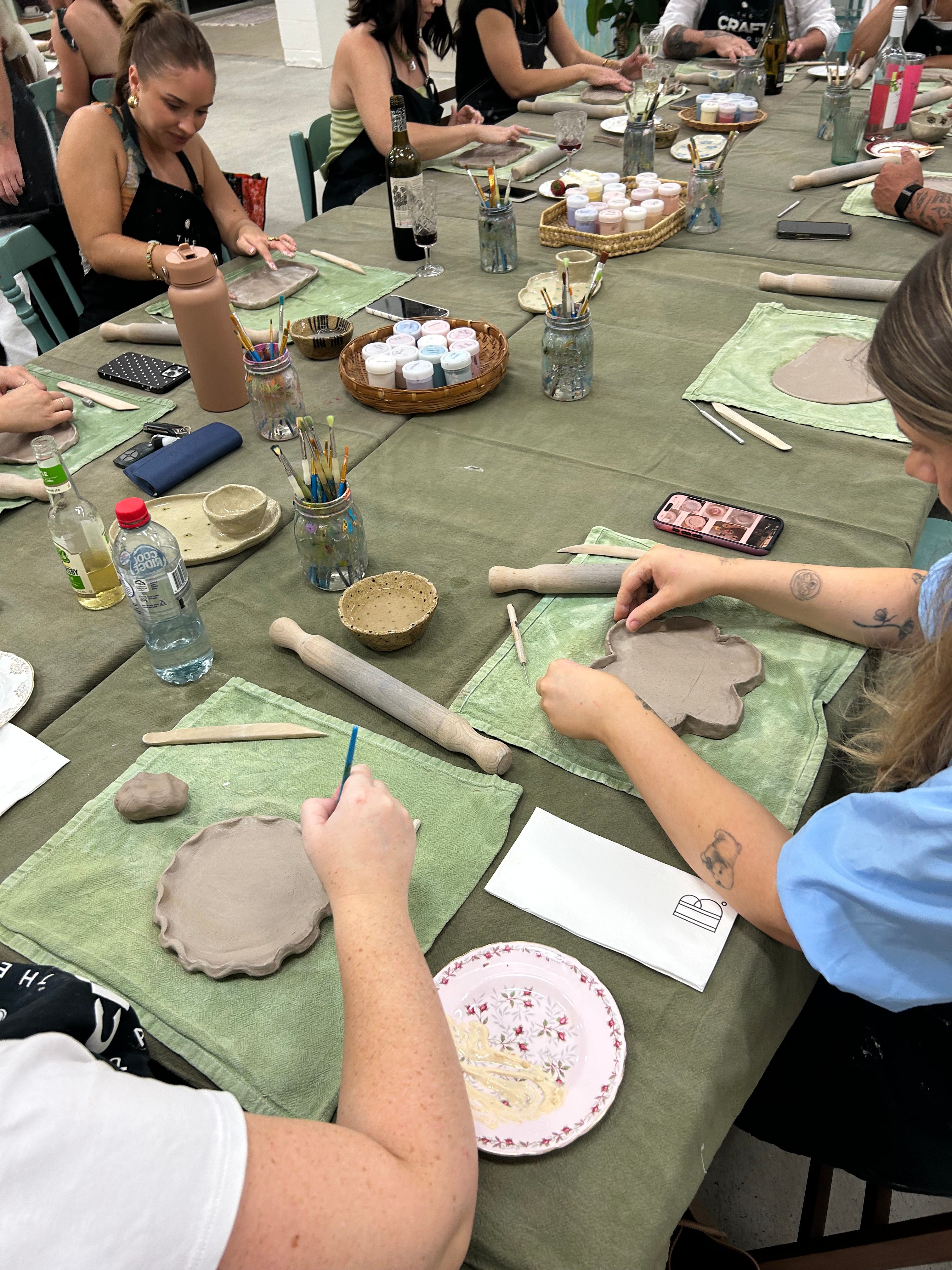 People working with clay at a pottery workshop on a table.