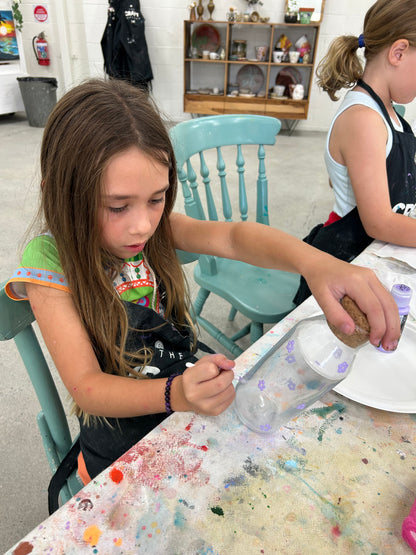 Child working on a craft project at a table with various materials.