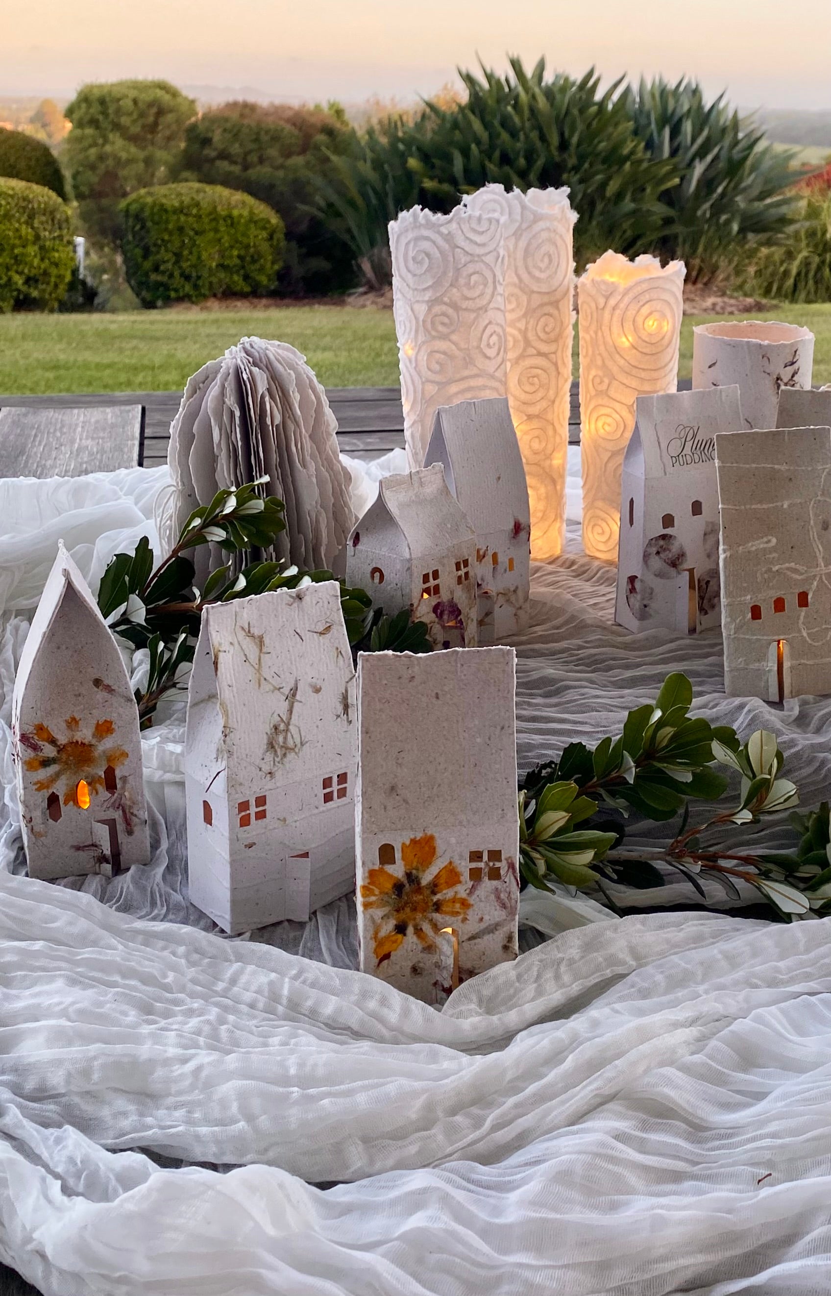Decorative paper houses and lights on a white cloth outdoors