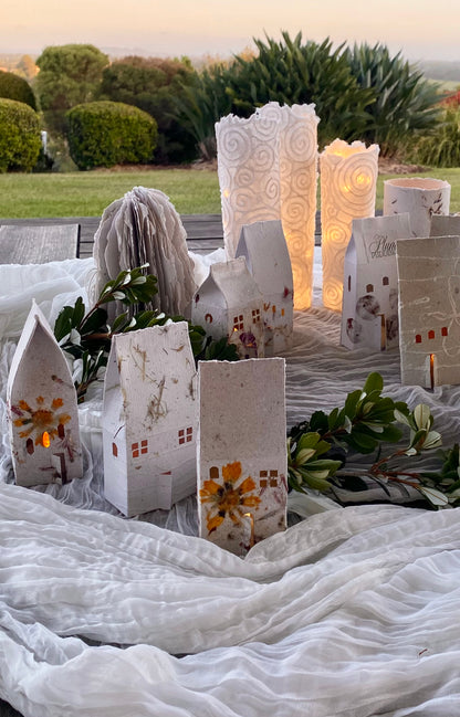 Decorative paper houses and lights on a white cloth outdoors