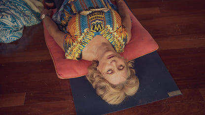Person lying on a yoga mat with colorful attire on a wooden floor