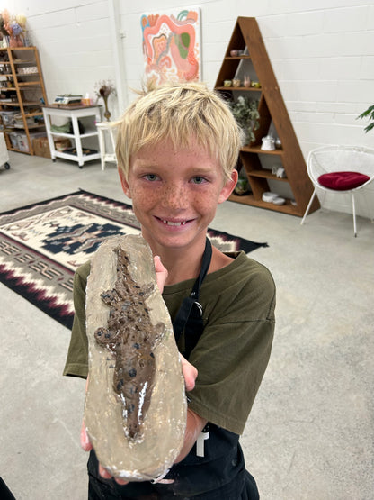 Young boy holding a clay crocodile in our studio