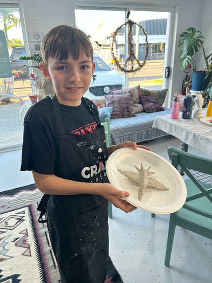 Child holding a clay plane in our studio