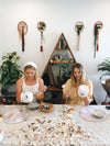 Two girls making shell mosaic pots with lots of shells to choose from