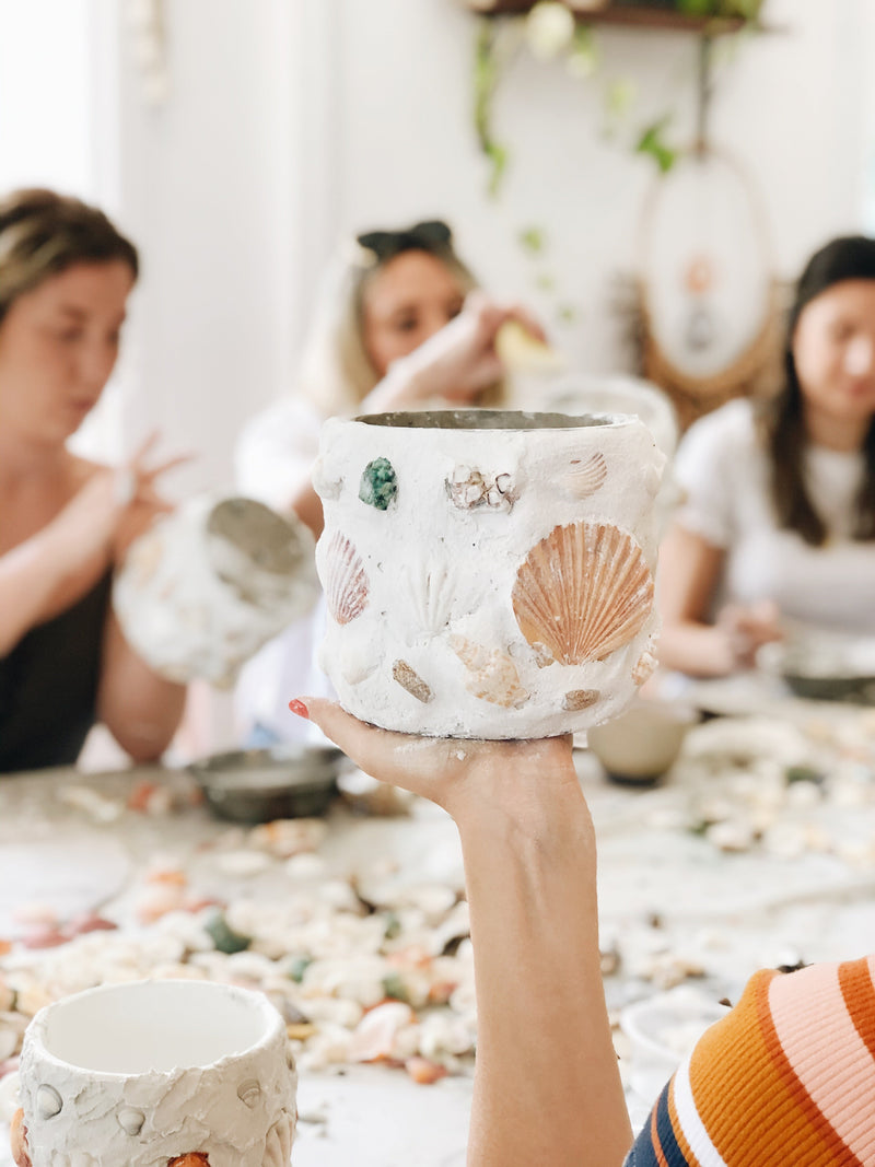 A beautiful shell mosaic pot being held up in class