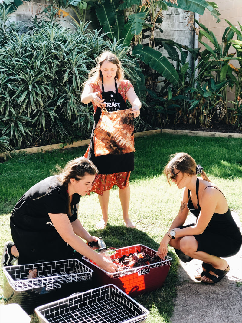 Three ladies hand dyeing their pieces in the sun