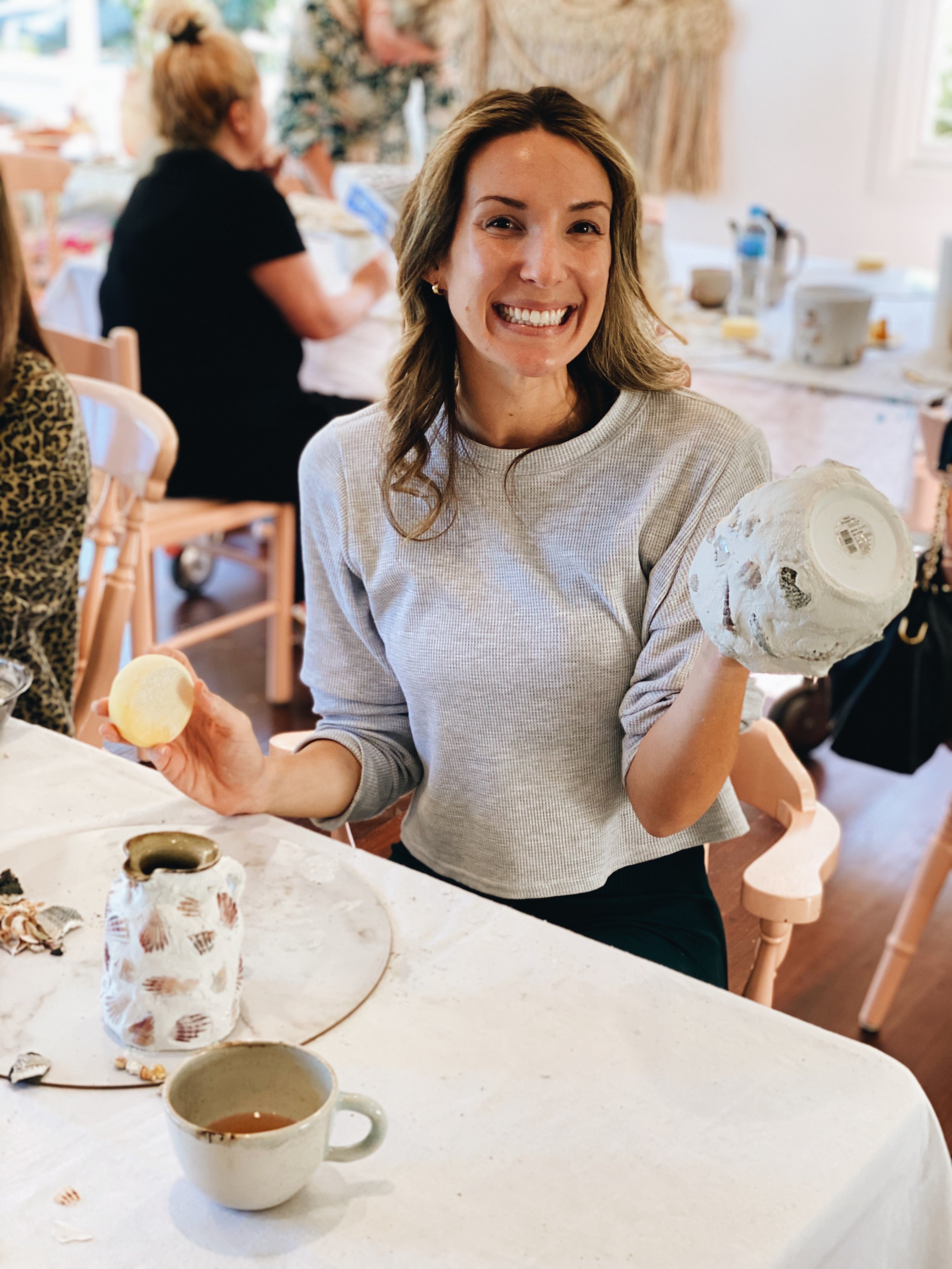 Smiling lady making her shell mosaic pot during class