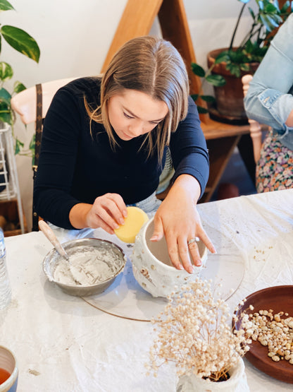 Lady paying close attention while making her shell mosaic pot