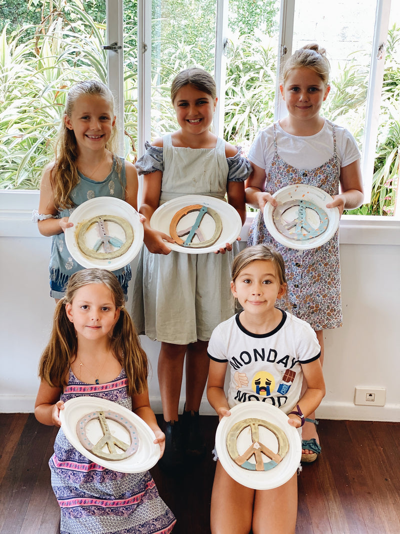 Group of girls with finished pottery peace signs handmade at kids pottery workshop Gold Coast